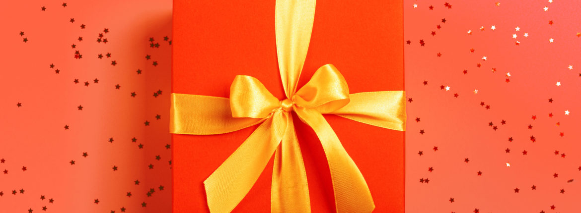 red box tied with a gold ribbon. the ribbon is tied on a box in the form of a beautiful bow. holiday gift concept